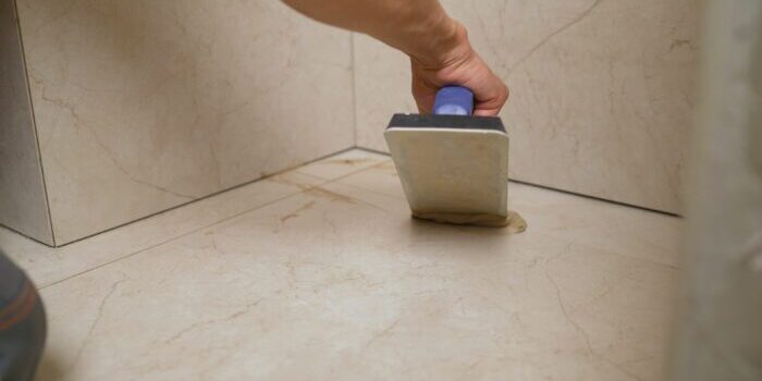 The master is rubbing the seams of tiles on the floor. Final finishing works with ceramic tiles. Close-up - hands, wiping interlayer tabs with putty, seams. A two-component, decorative, acid-resistant epoxy grout. Final finishing works with ceramic tiles. Close-up - hands, wiping interlayer tabs with putty, seams. A two-component, decorative, acid-resistant epoxy grout. The master is rubbing the seams of tiles on the floor.